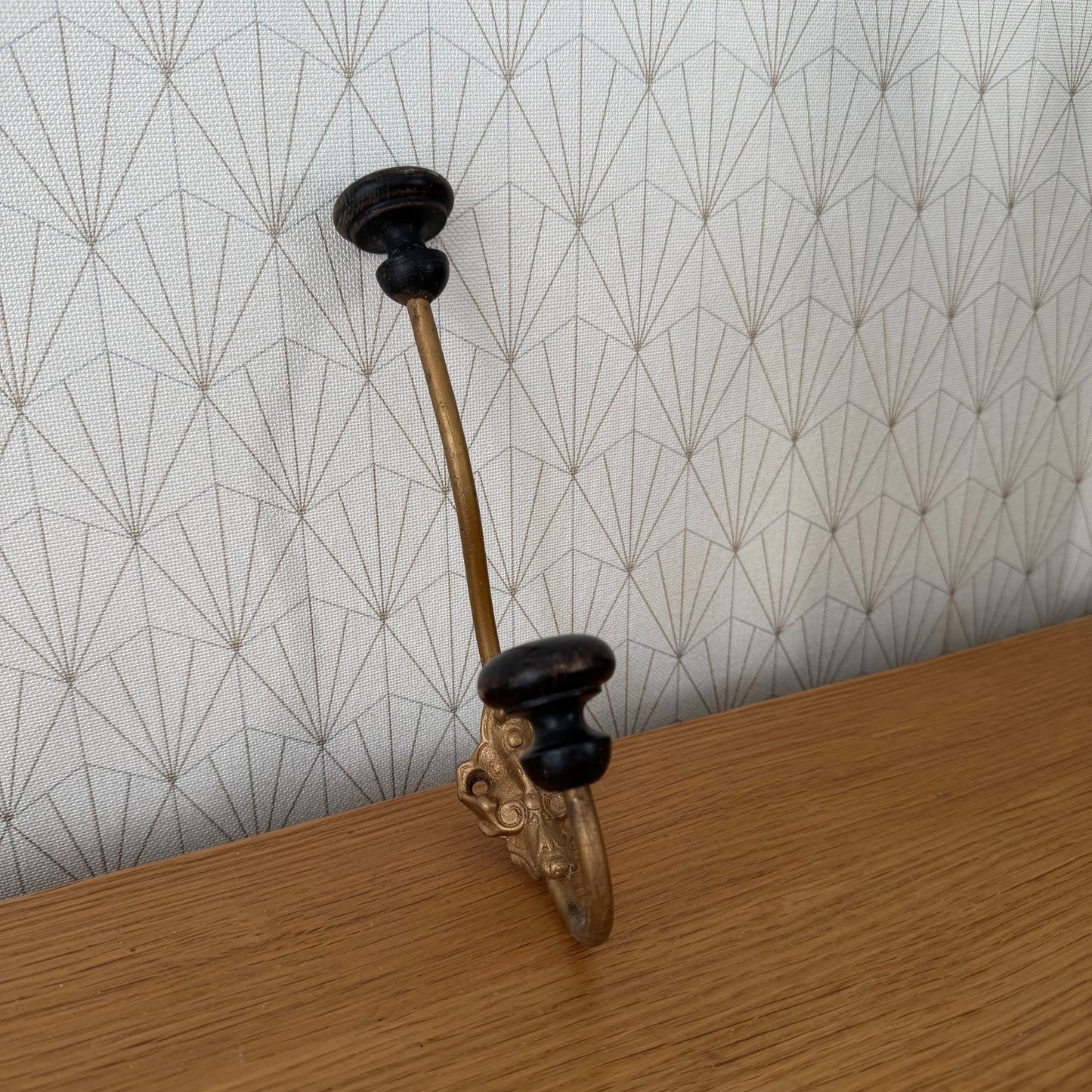 Side profile of vintage French metal wall hook showing curved hook design and wooden knob