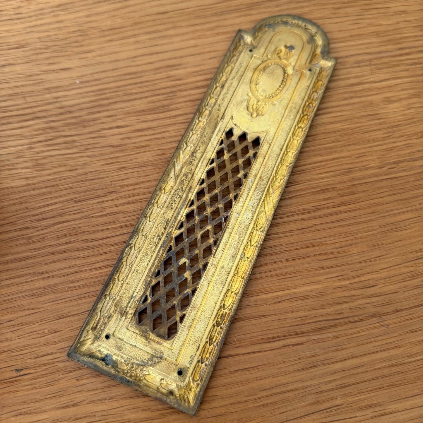 Overhead view of complete set of 6 French vintage brass door plates fanned out on wooden surface