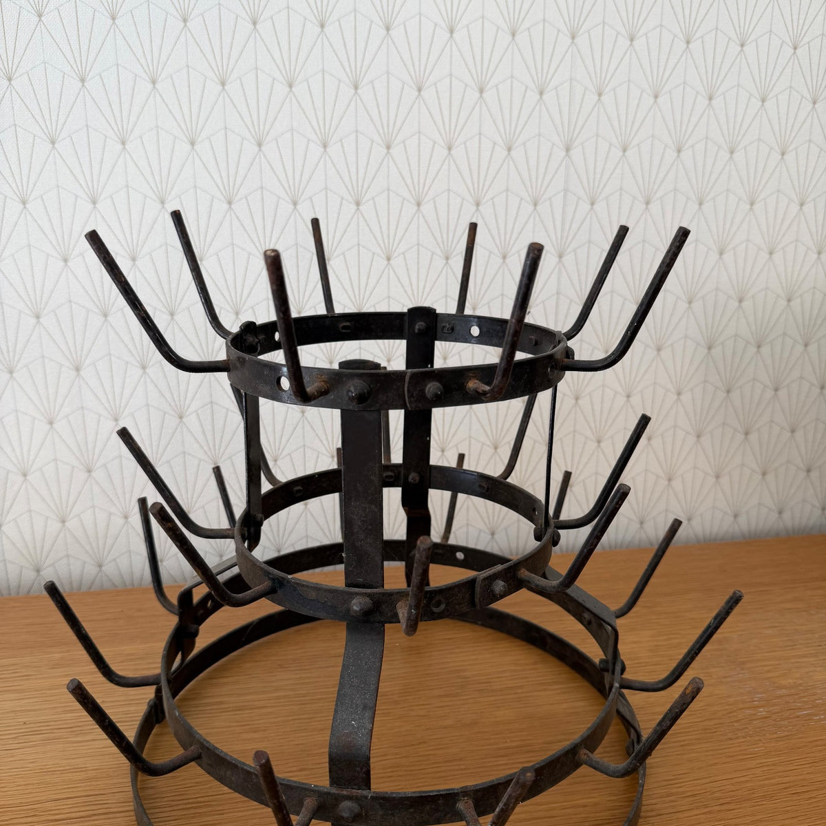 Detailed view of three-tiered French iron bottle drying rack showing traditional hand-riveted assembly