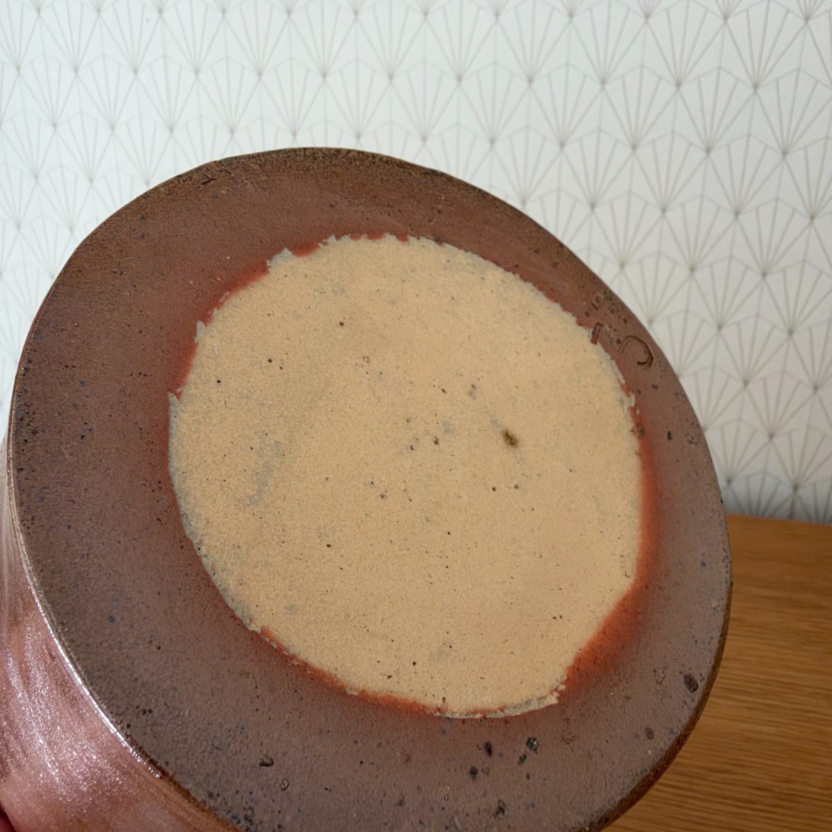 Unglazed foot base of antique French stoneware pitcher showing pale buff clay body and kiln marks.