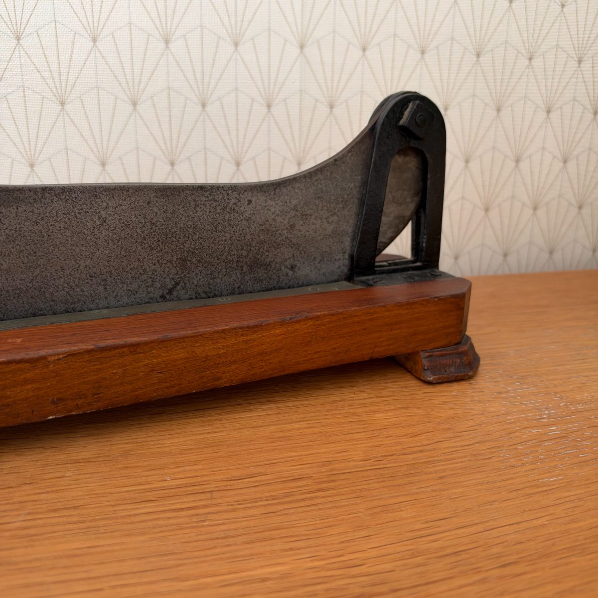 Close-up of the pivot end of the antique French cast iron bread slicer showing cast iron arch bracket and blade hinge mechanism.