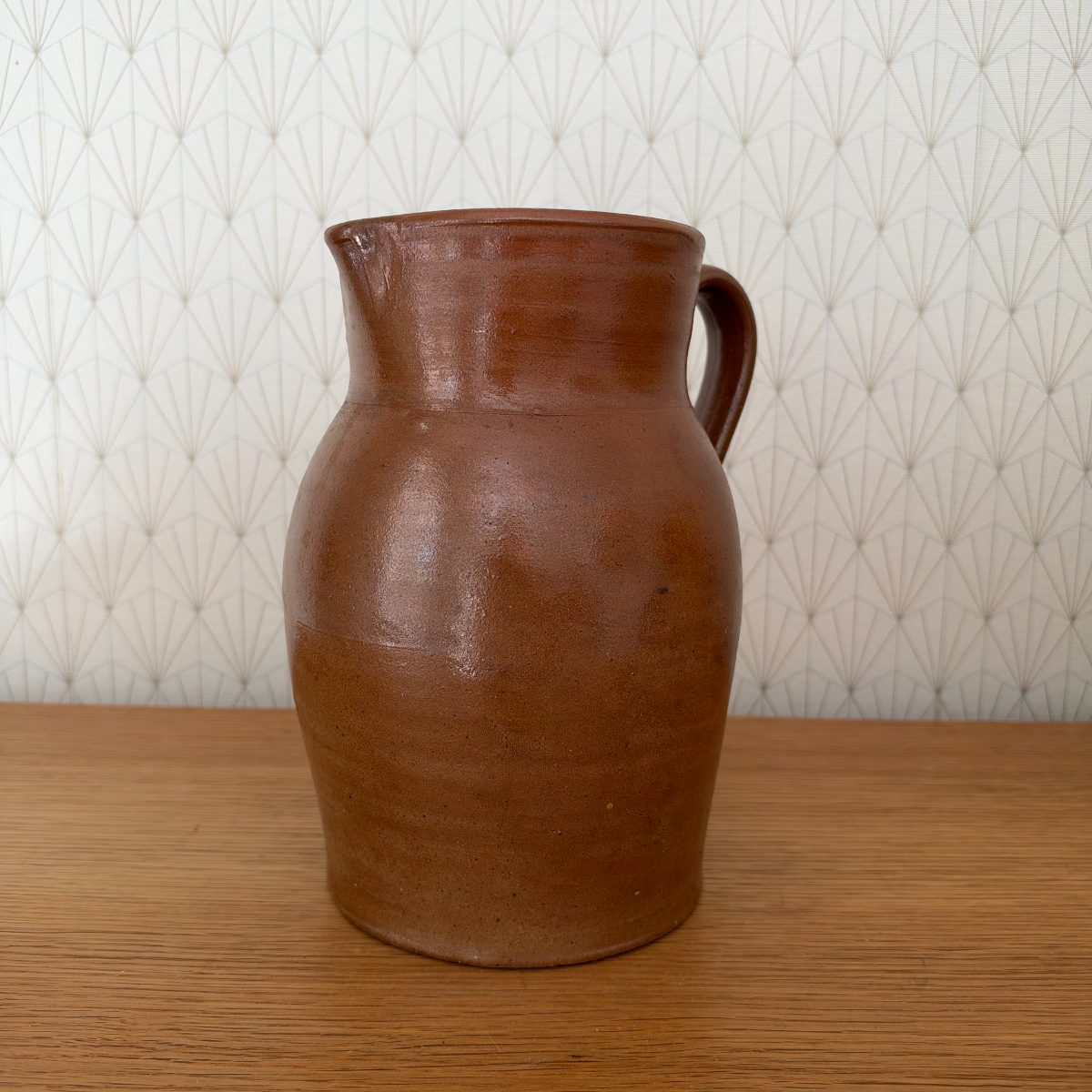 Opposite side of antique French stoneware pitcher showing spout and loop handle detail.