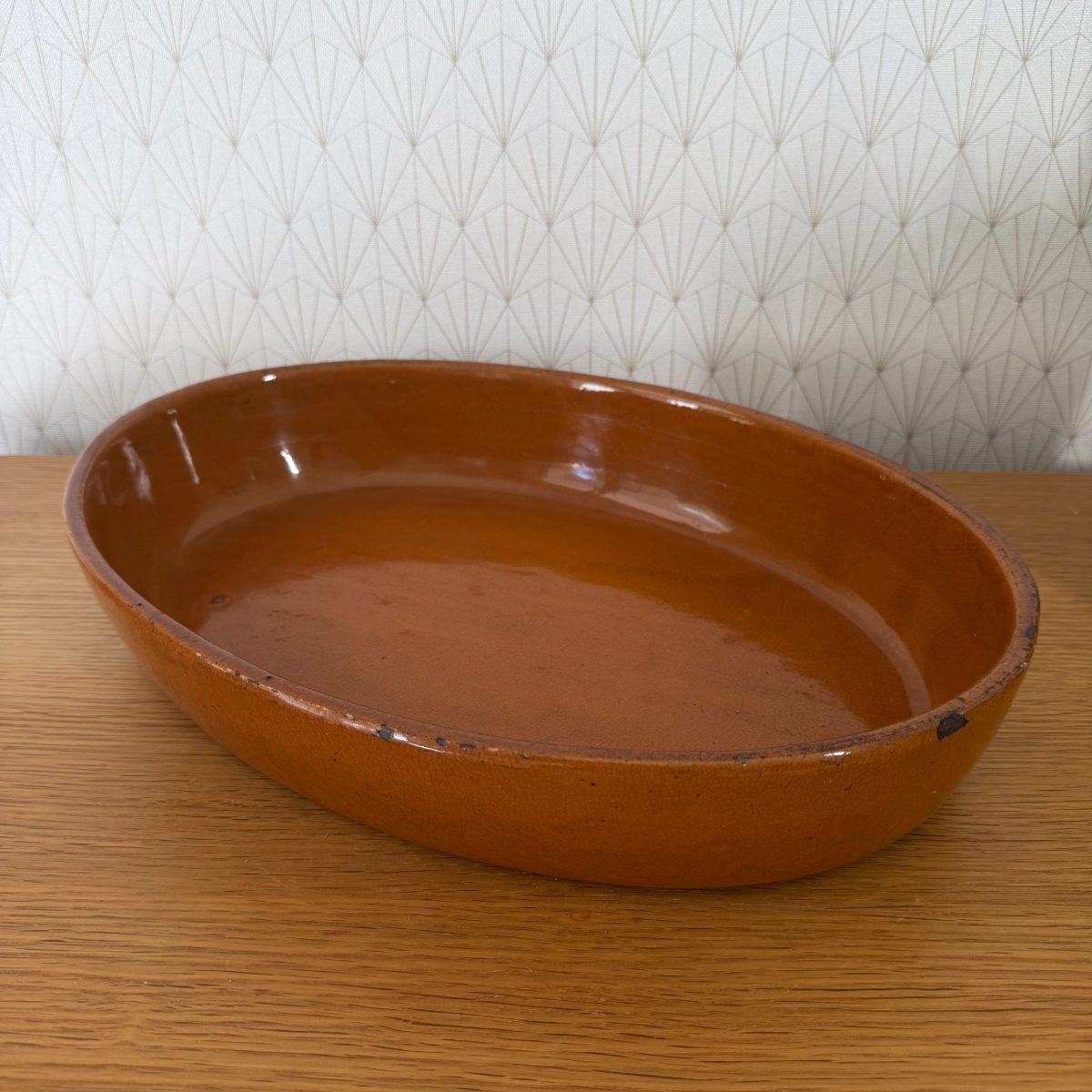 Top angle view of French oval terracotta baking dish showing deep amber glaze interior and unglazed exterior walls.