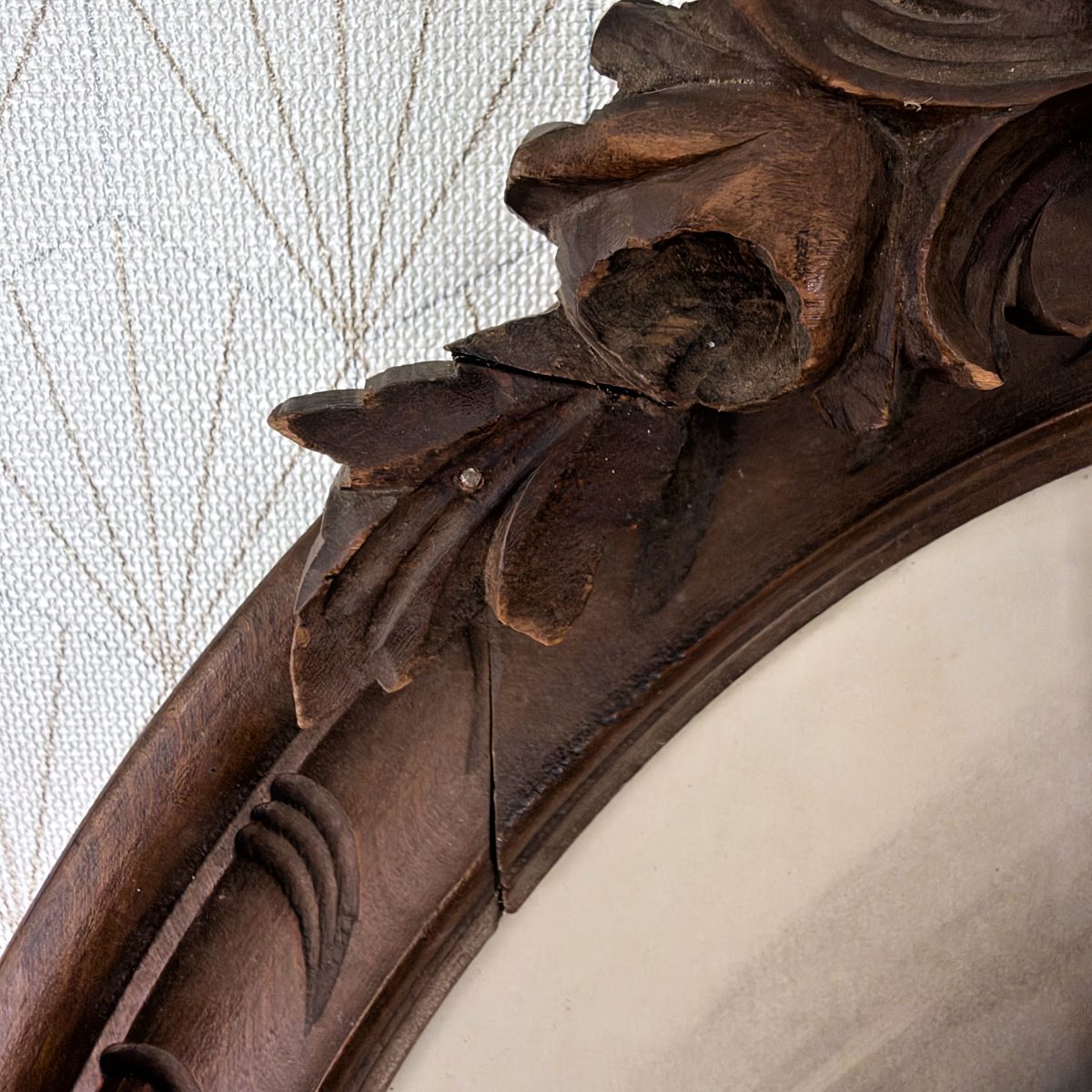Close-up of upper left side of antique French oval carved frame showing chipped and repaired area in carved leaf decoration, honest condition detail.