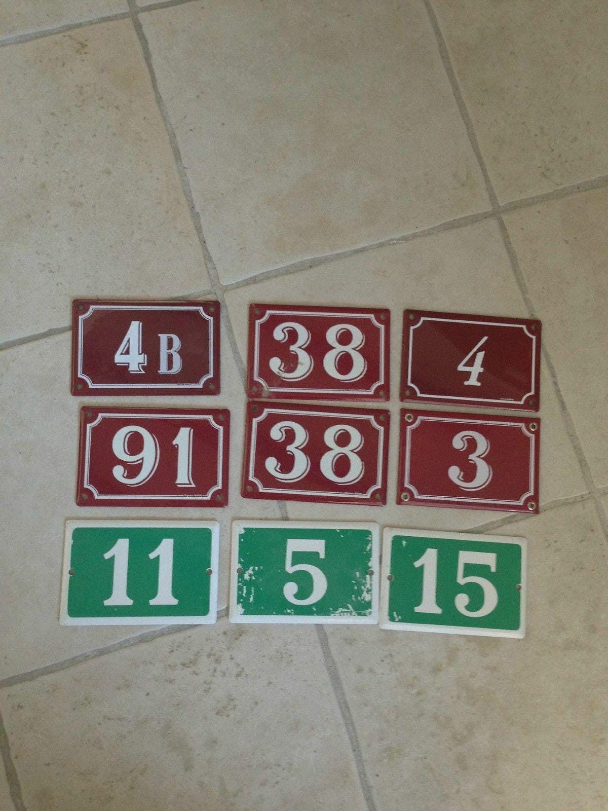 Collection of authentic French enamel door number signs including digits 3 4 5 11 15 38 91 and 4B on metal plates with traditional enamel finish in red and green colorways.