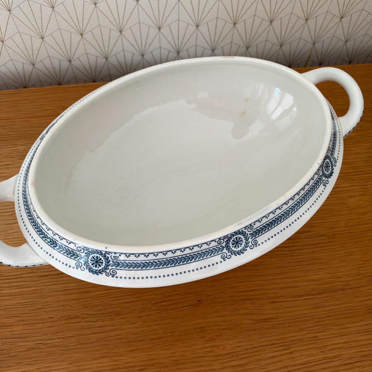 Top-down view of antique French ironstone tureen base interior showing plain white glaze with light age staining and blue decorated rim.