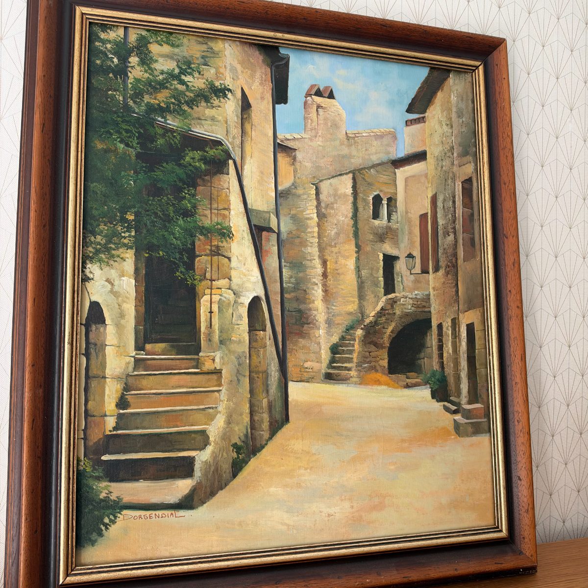 Close angled view of French oil painting on canvas depicting a sunlit village square with stone arches and steps, signed Dorgendial lower left.
