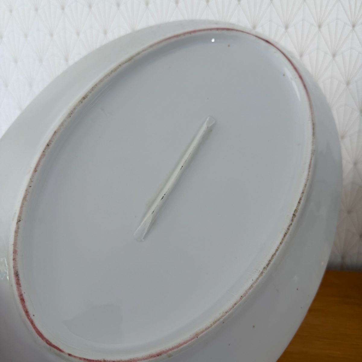 Underside of antique French white ironstone oval platter showing unglazed foot ring, single raised ridge and accumulated patina.