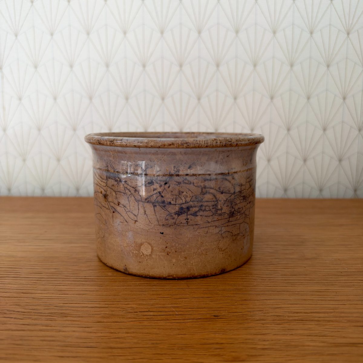 Antique French Sarreguemines stoneware crock pot, beige and blue-grey glaze with crazing, front view on oak surface.