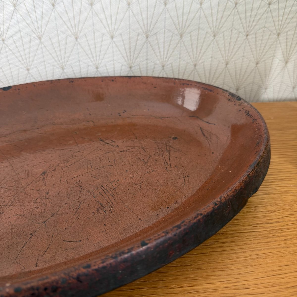 Close-up of the lower right section of the French terracotta oval dish showing heavy use scratches and dark rim detail.