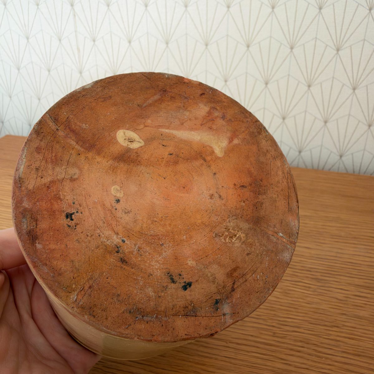 Bottom of antique French stoneware jam pot showing unglazed red terracotta base with tool marks and age patina.
