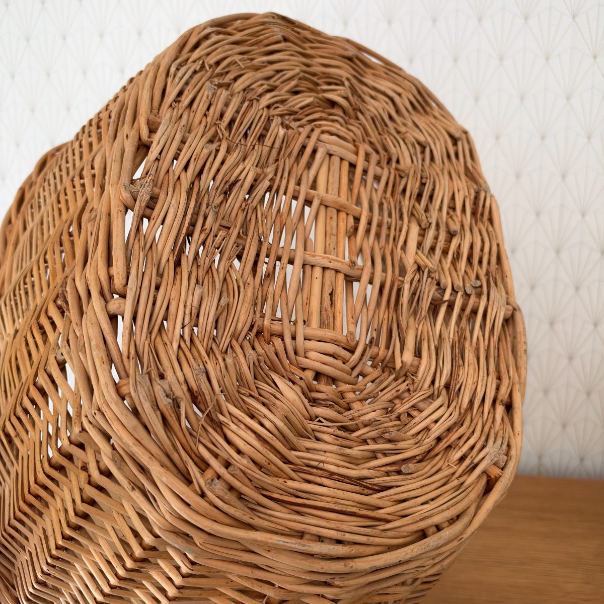 Close-up of the underside and base of vintage French wicker laundry basket showing dense rattan weave and natural age patina.