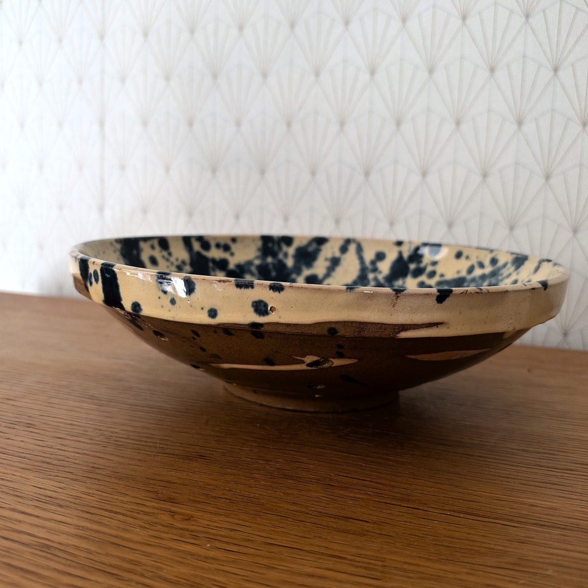 Side profile of vintage French splatter glaze earthenware colander bowl showing unglazed brown exterior and wide flat rim.