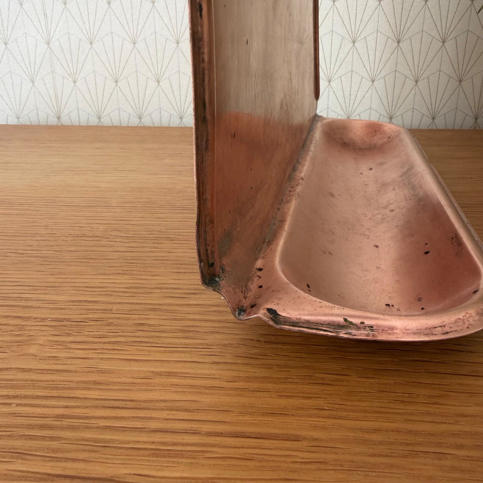 Close-up of curved copper base shelf and mounting hardware of vintage utensils hanger