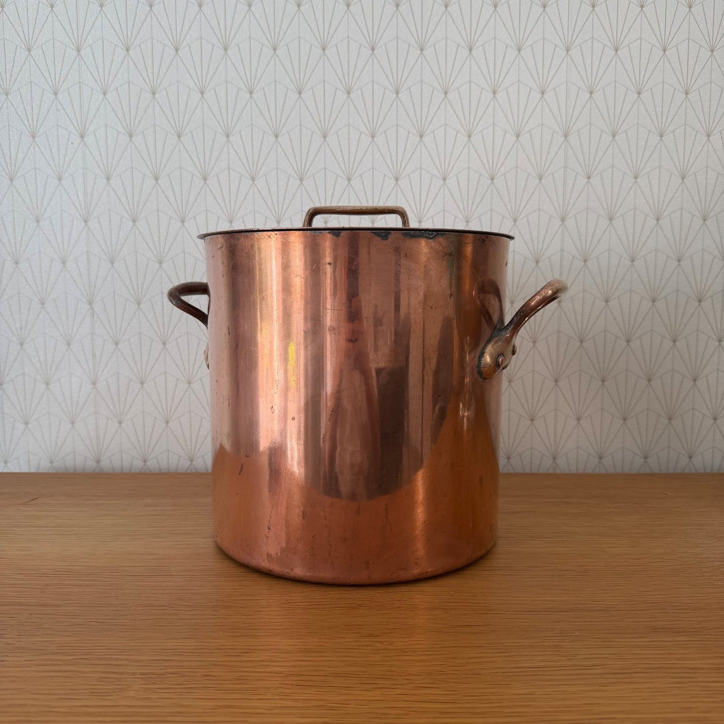 Side profile of large antique French copper stock pot with side handle and lid