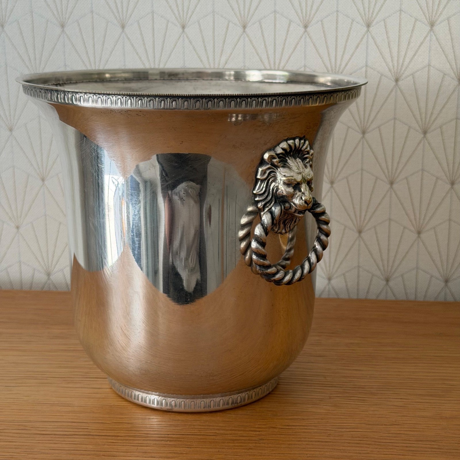 Close-up detail of cast lion head handle on vintage French silverplate champagne bucket