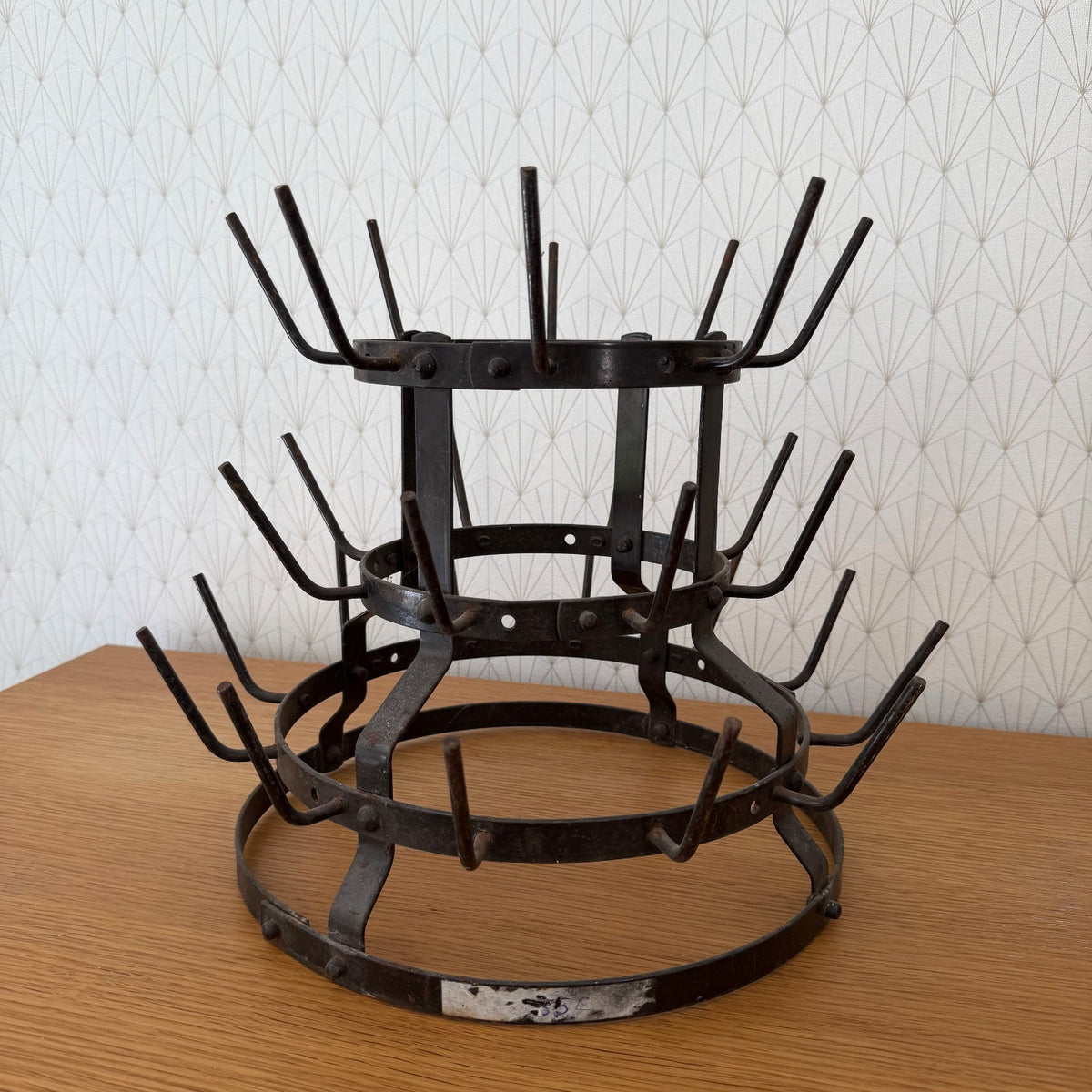 Front view of authentic French wrought iron bottle rack with curved support legs and tiered design