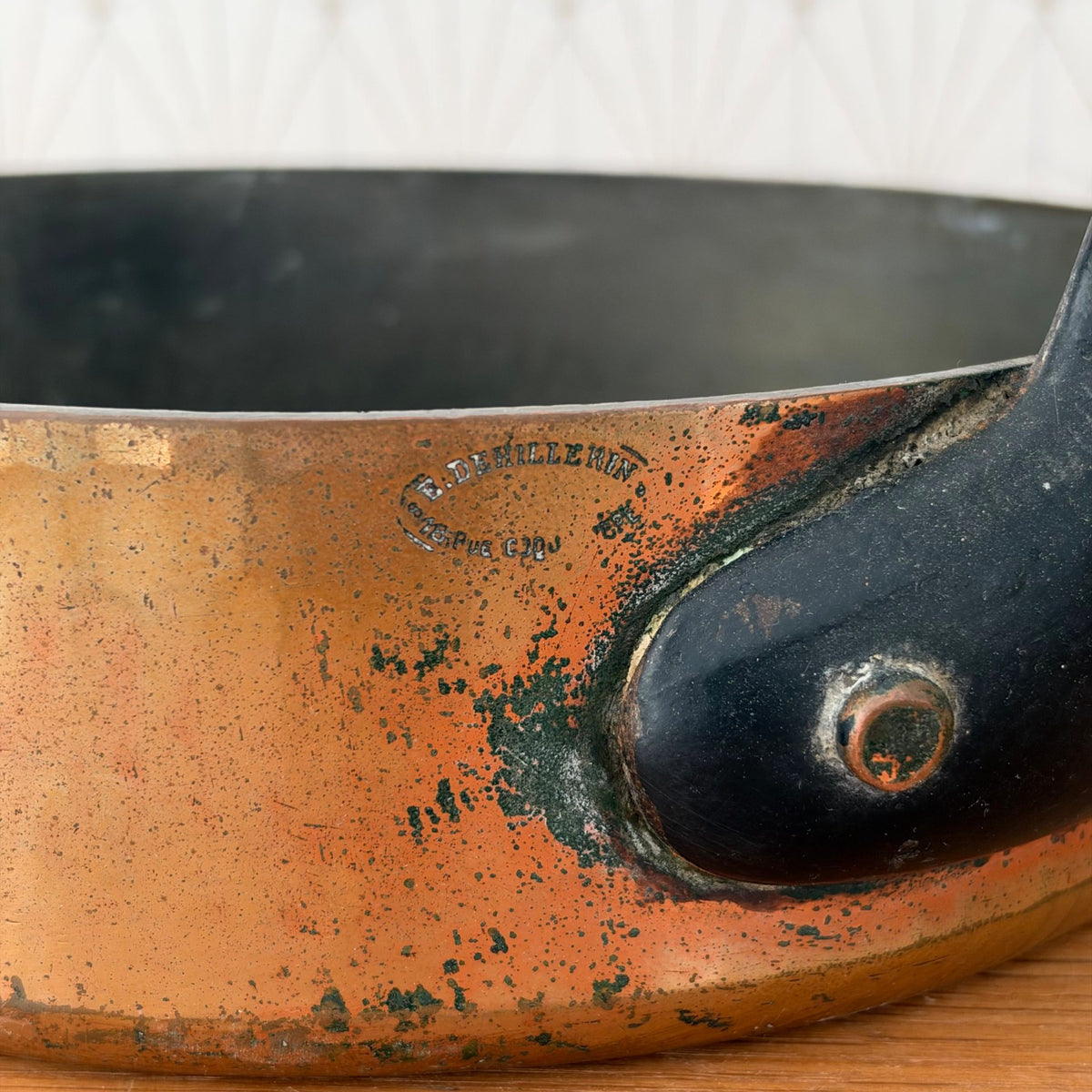 Detail of black iron handle attachment with rivets on copper cookware