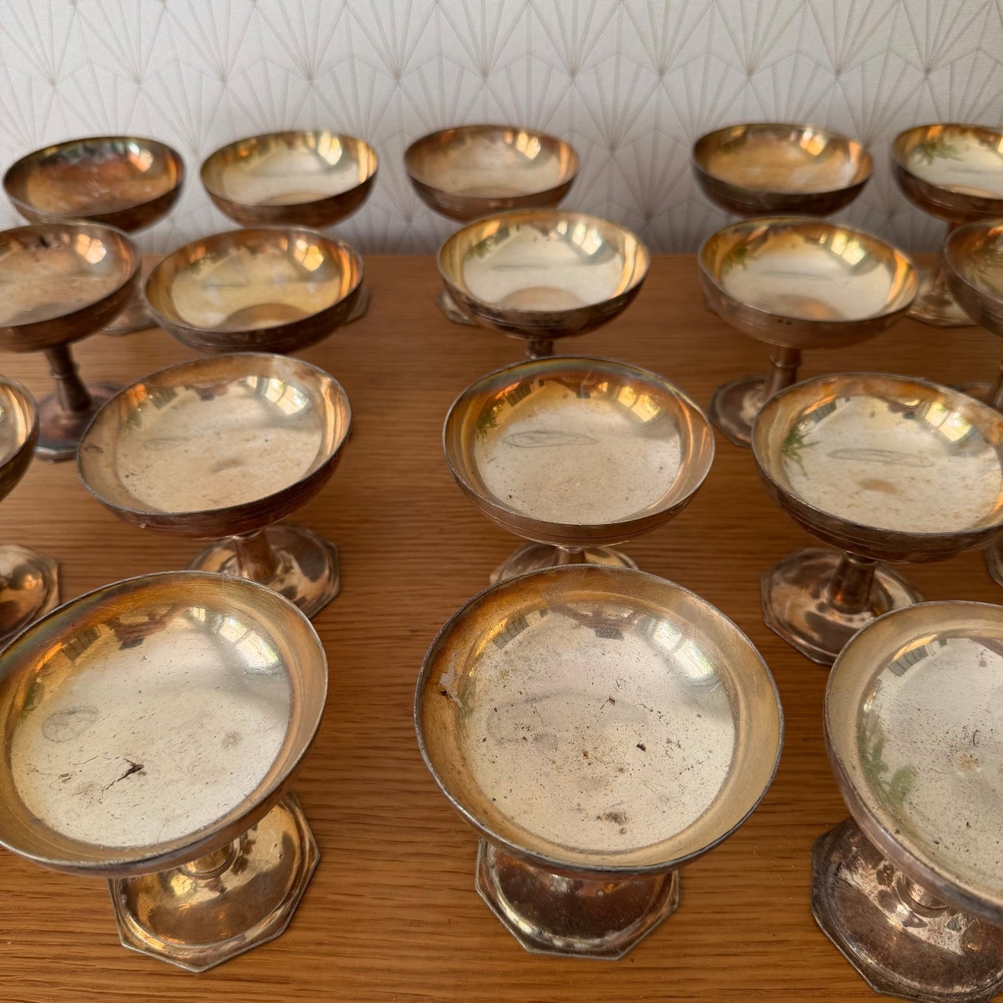 Row of vintage silverplate champagne coupes displaying consistent form across complete set of 20 pieces