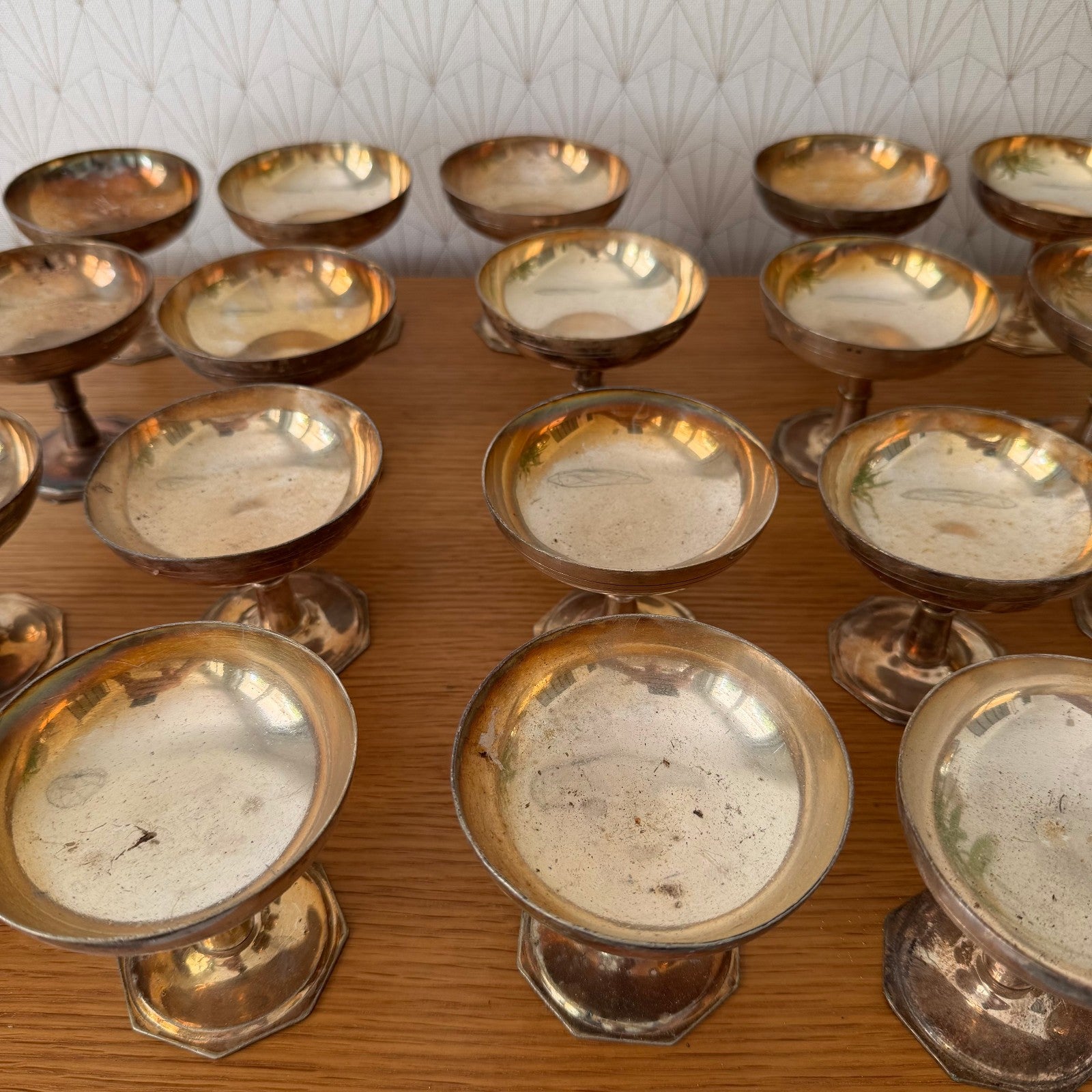 Row of vintage silverplate champagne coupes displaying consistent form across complete set of 20 pieces