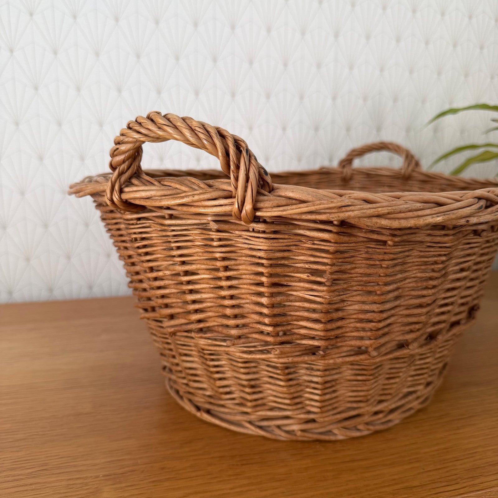 Angled side view of authentic French rattan laundry basket with warm honey-brown patina