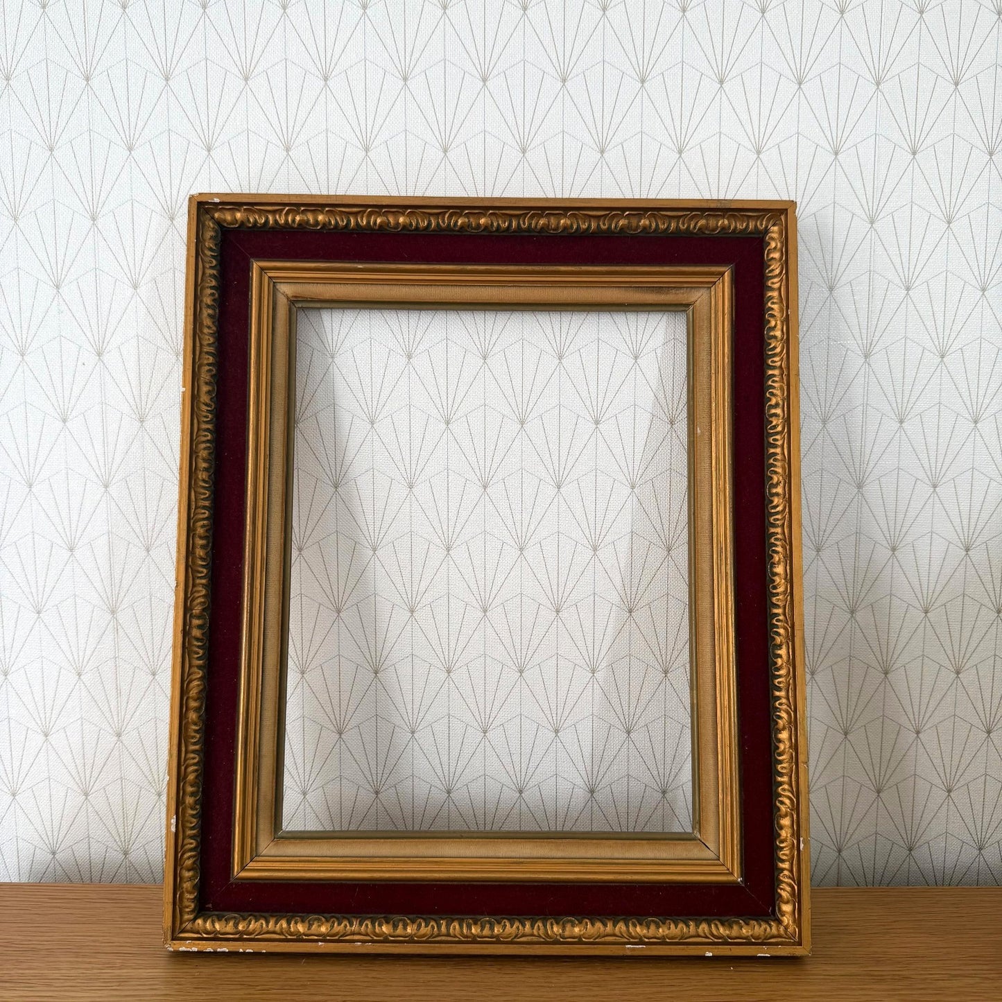 French vintage gold picture frame with red velvet inner mat, displayed against geometric patterned wallpaper