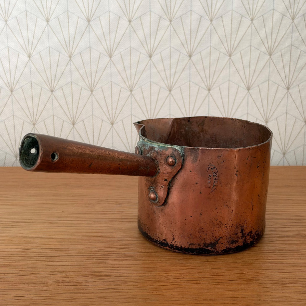 Full view antique French copper sugar pan with long wooden handle and pouring spout