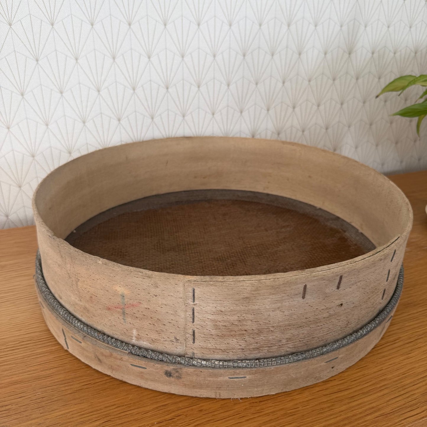 Side angle of French wooden sieve showing stapled seam and metal reinforcement band