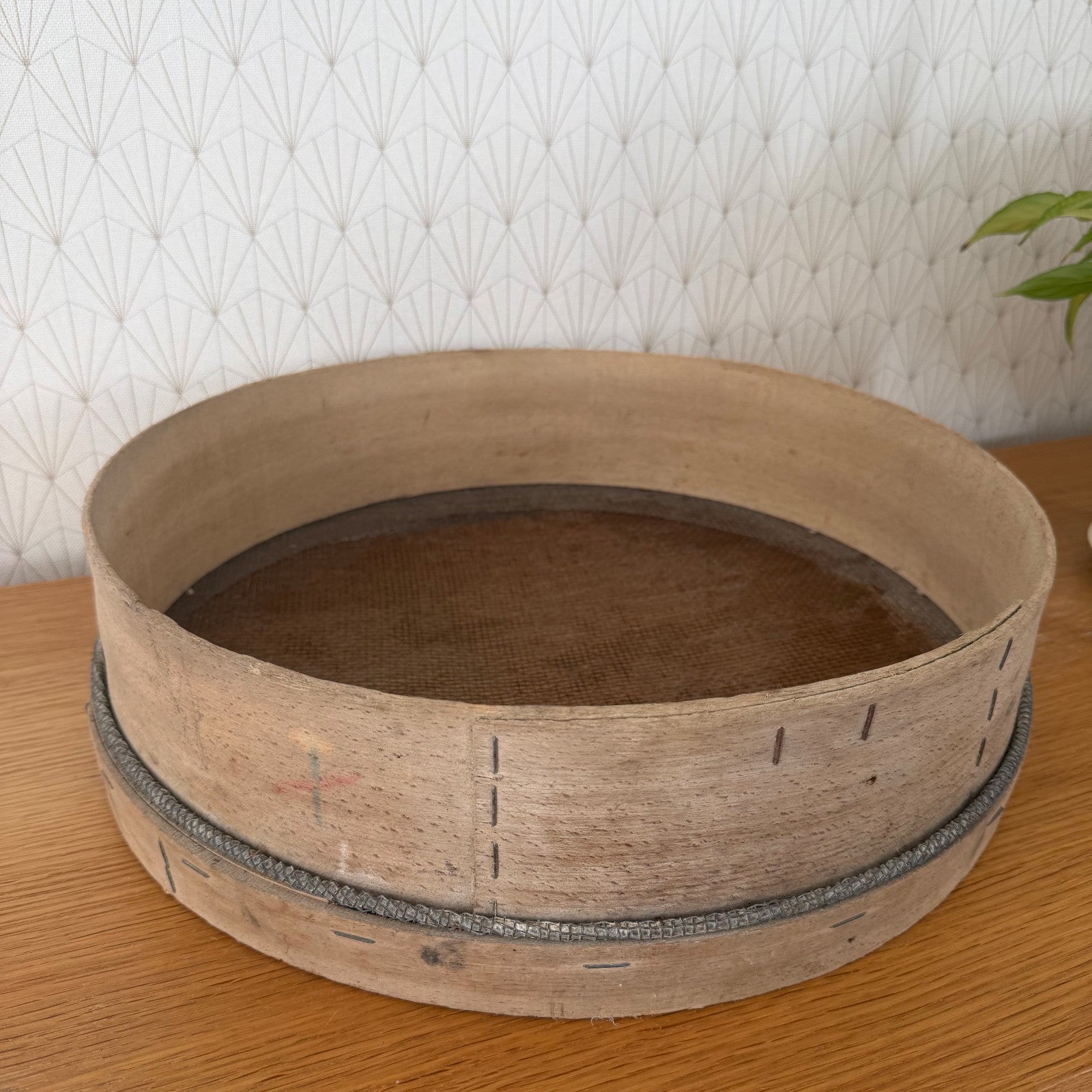 Side angle of French wooden sieve showing stapled seam and metal reinforcement band