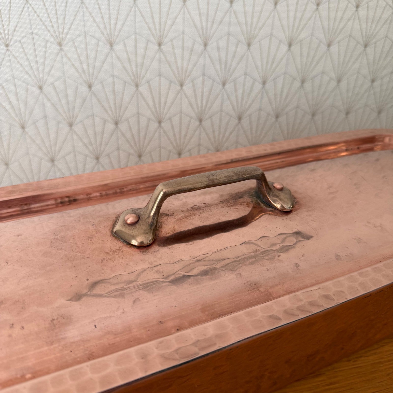 Close-up of brass handle and hinged lid mechanism on copper fish poacher