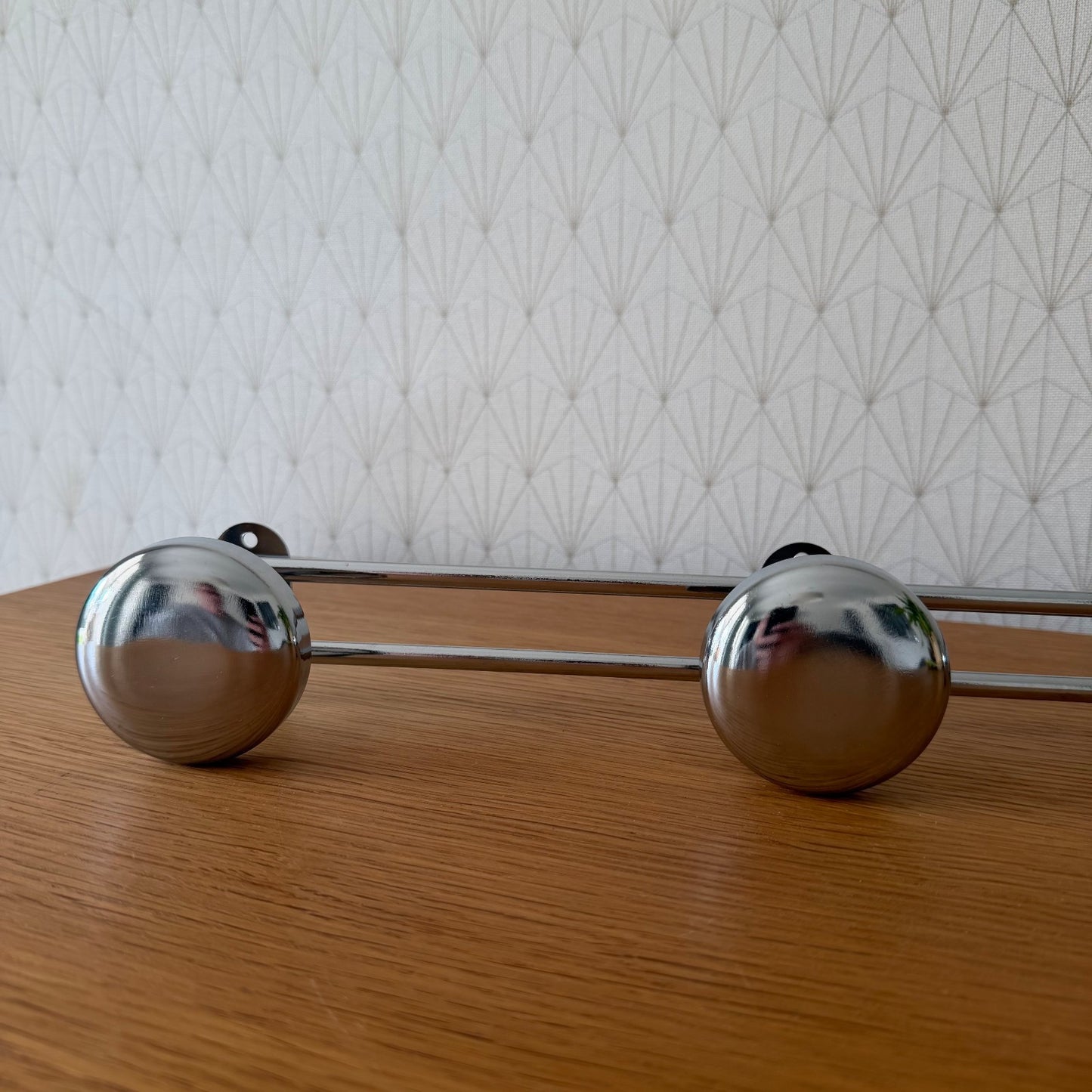 Side profile of mid-century chrome coat rack with geometric wall pattern background