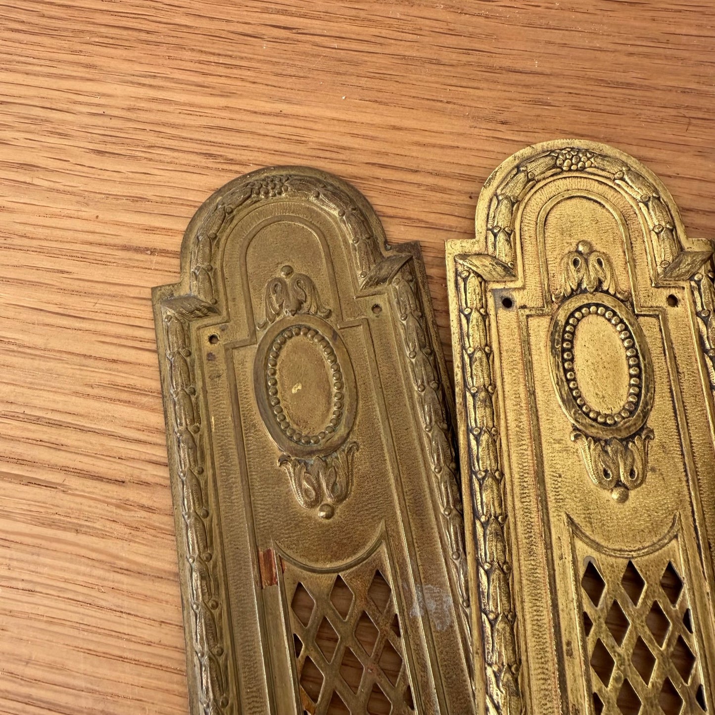 Close-up detail of two French vintage door finger plates showing beaded oval centers and decorative borders