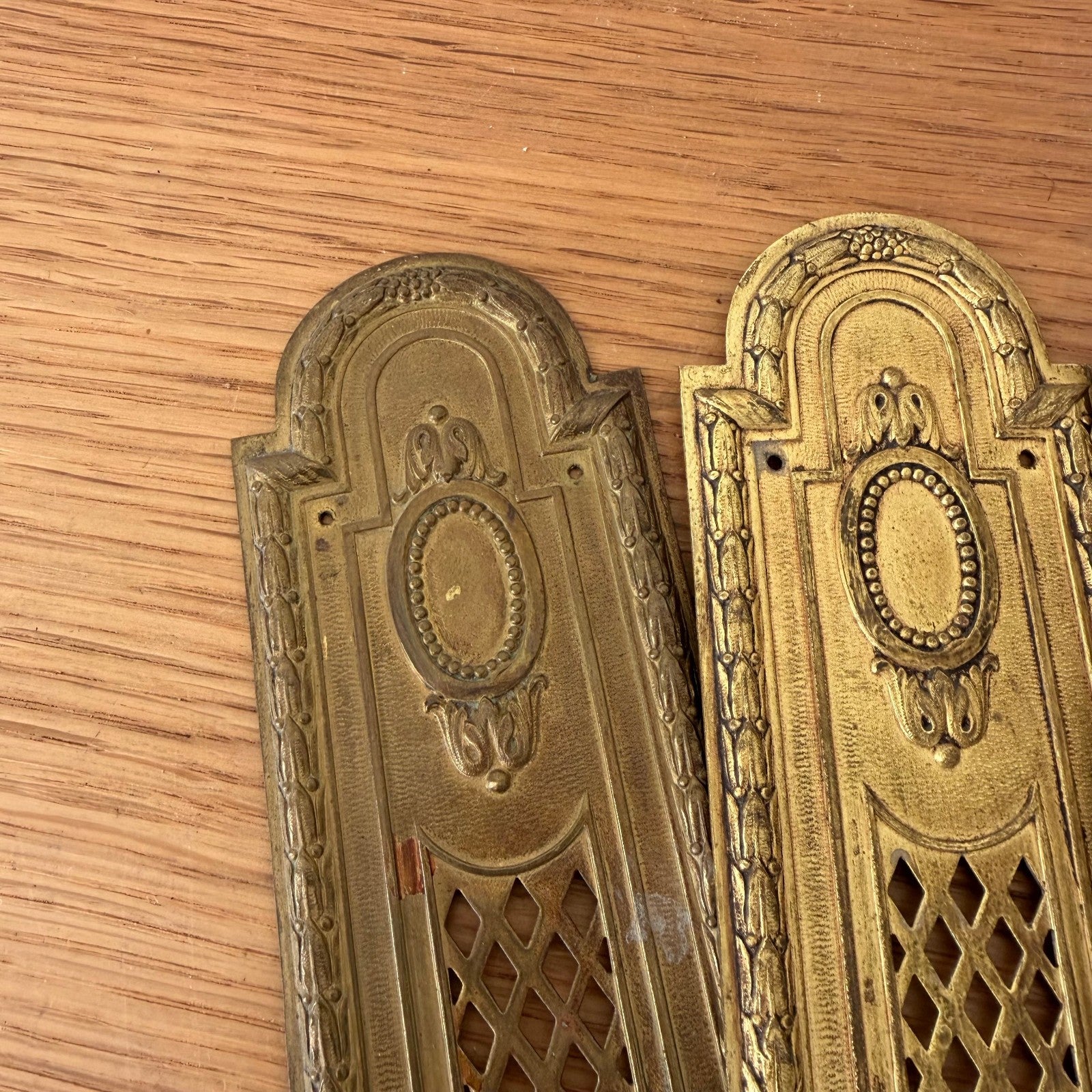 Close-up detail of two French vintage door finger plates showing beaded oval centers and decorative borders