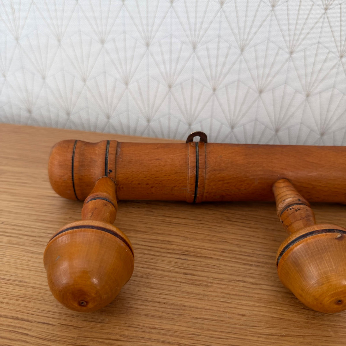 Close-up detail of wooden turned pegs with black-painted ring bands on vintage coat rack
