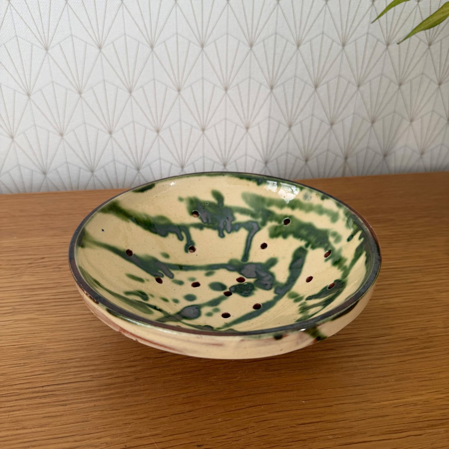 Hand-thrown French earthenware colander with two-tone glaze and perforated drainage holes, top view