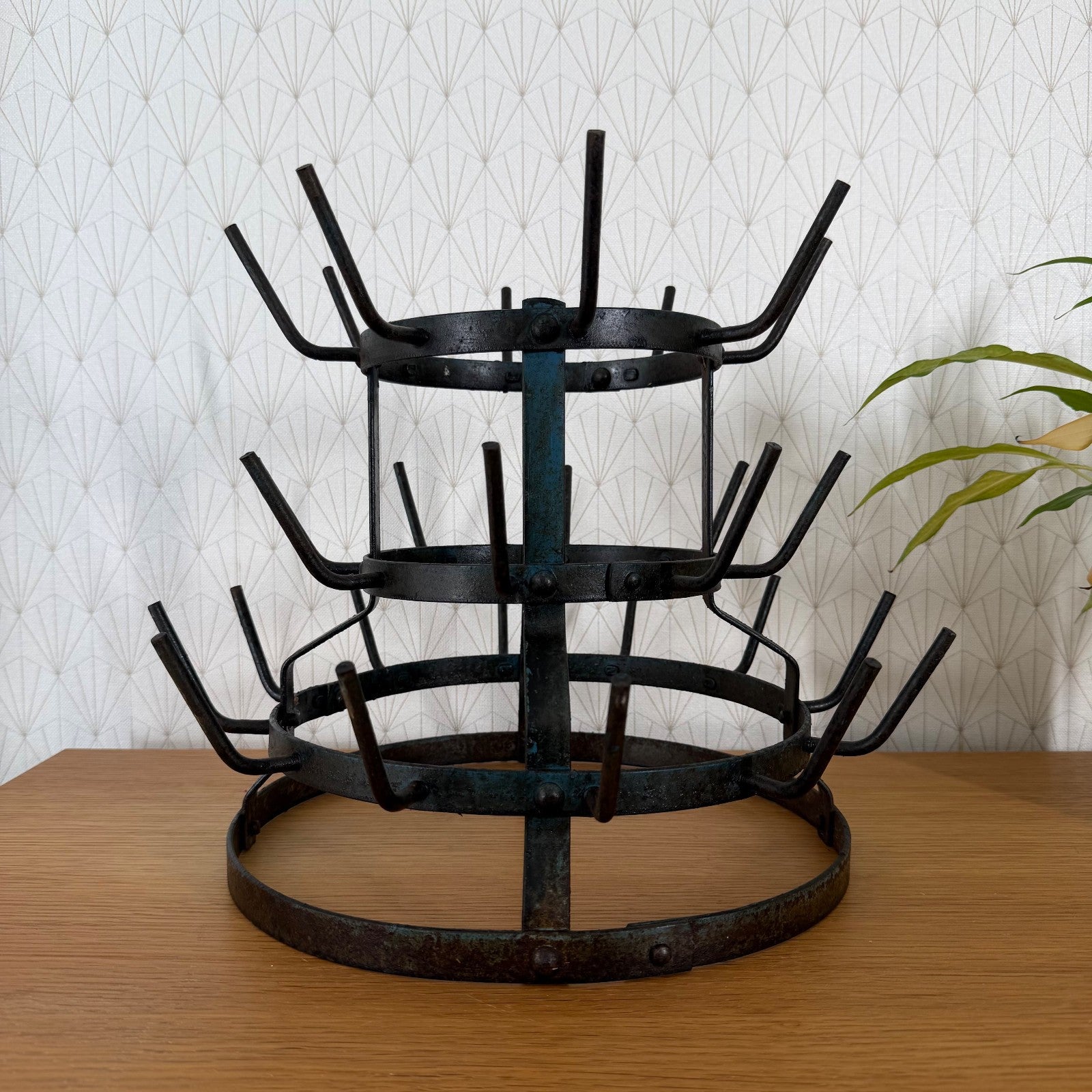Three-tier antique French wrought iron bottle drying rack with central spine and curved hooks, full view