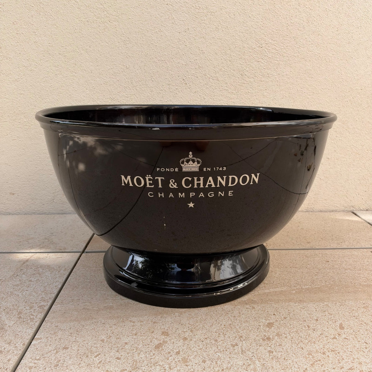 Moet Chandon black champagne bucket with white lettering and crown logo on pedestal base