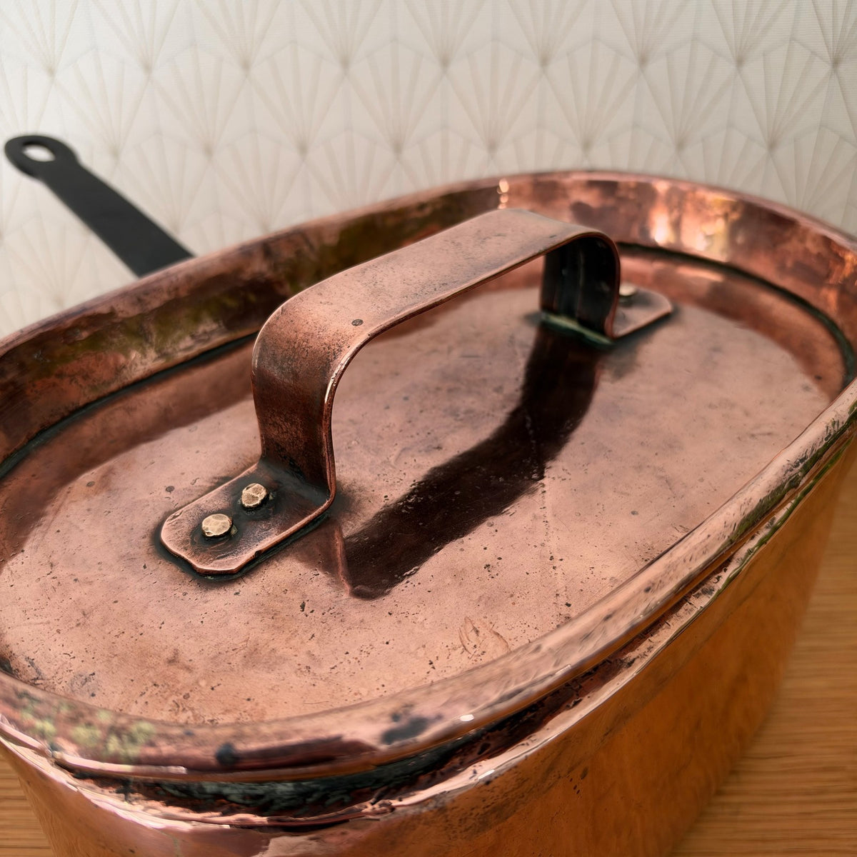 Close-up of copper braising pan lid with wrought-iron center handle and rivet construction