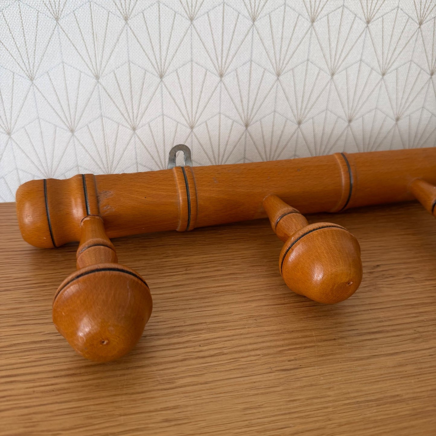 Close-up detail of bamboo coat rack showing turned wooden pegs with black accent rings