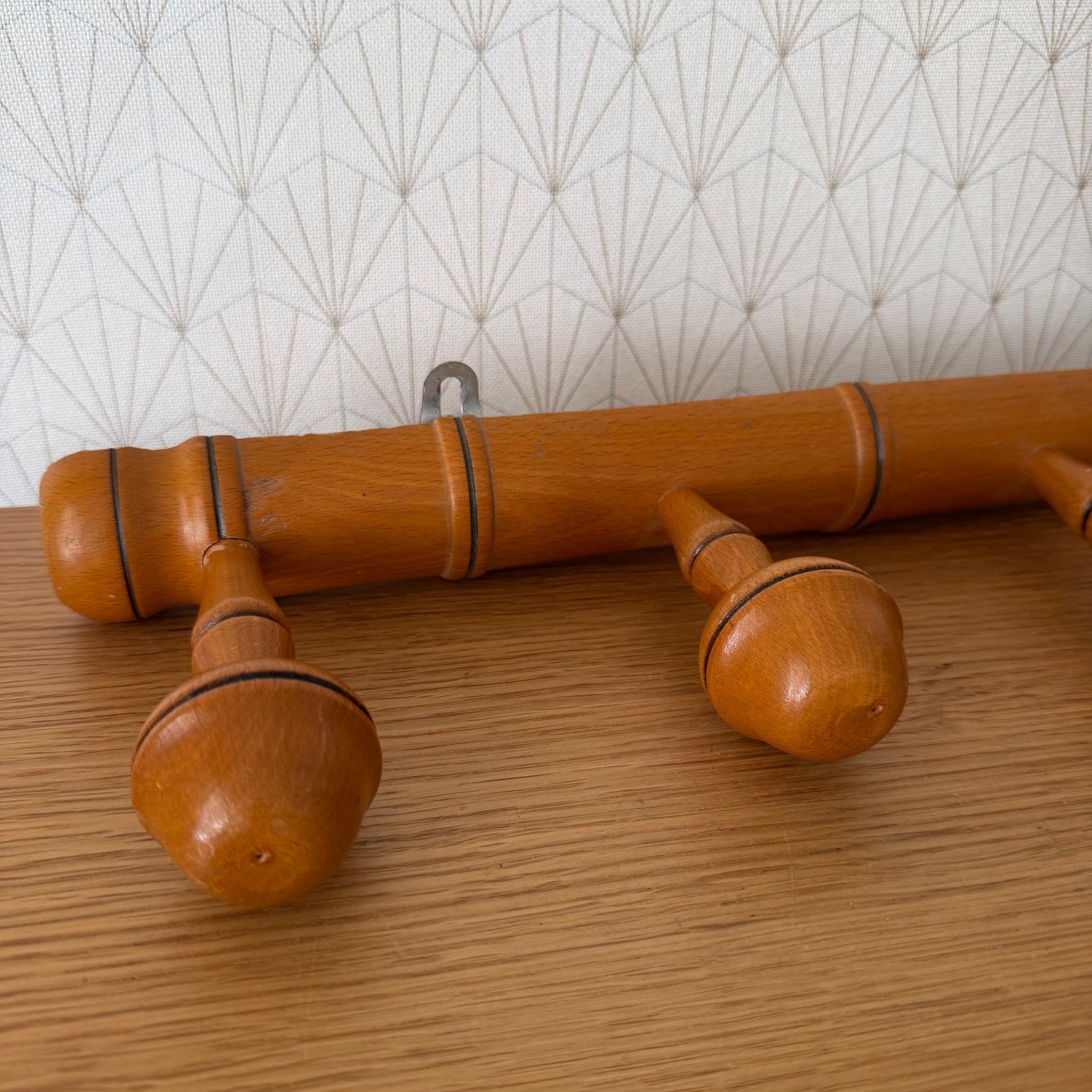 Close-up detail of bamboo coat rack showing turned wooden pegs with black accent rings