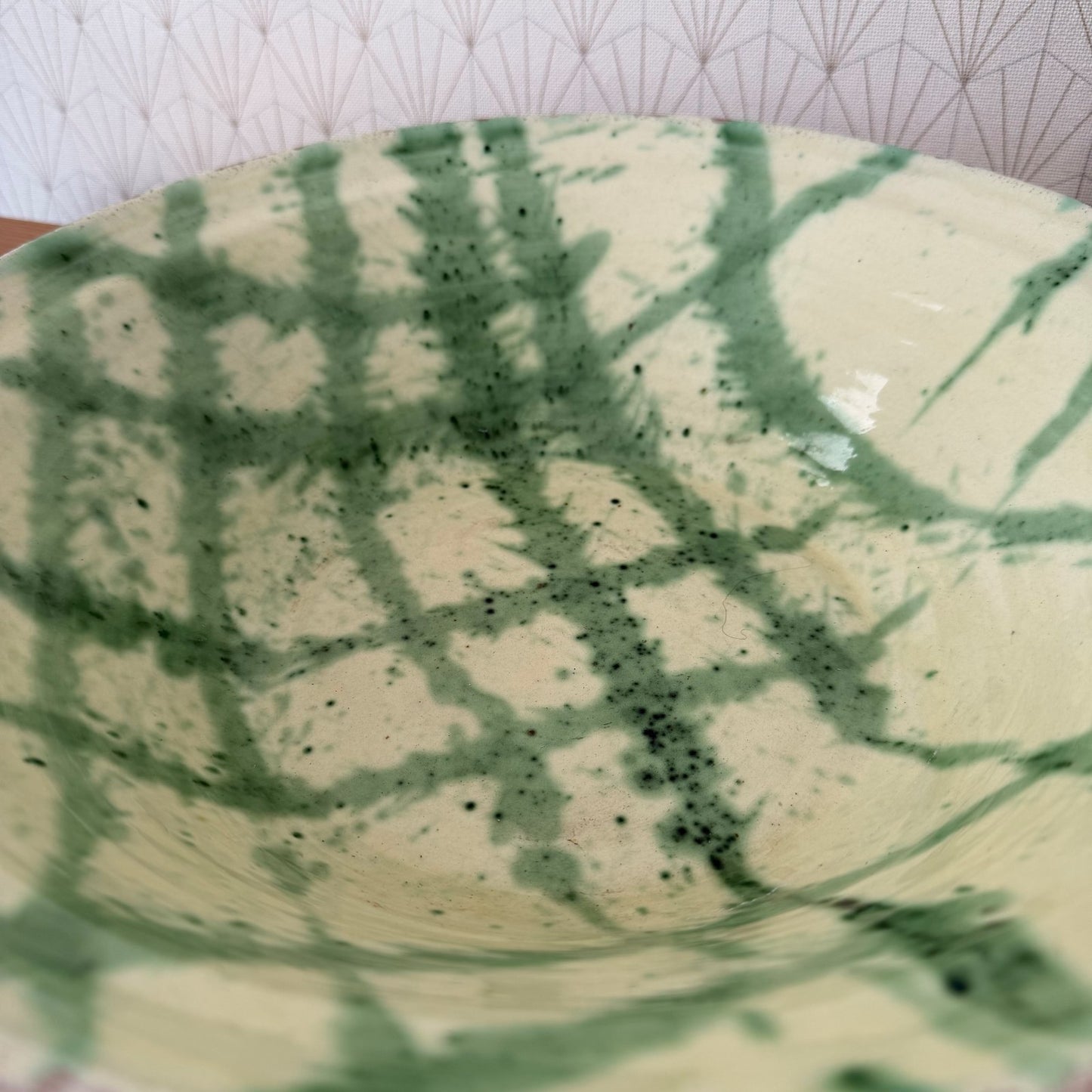 Close-up detail of green decoration and speckled glaze on French terracotta bowl interior