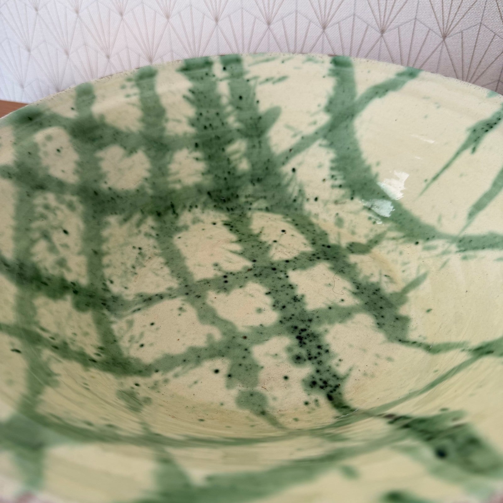 Close-up detail of green decoration and speckled glaze on French terracotta bowl interior