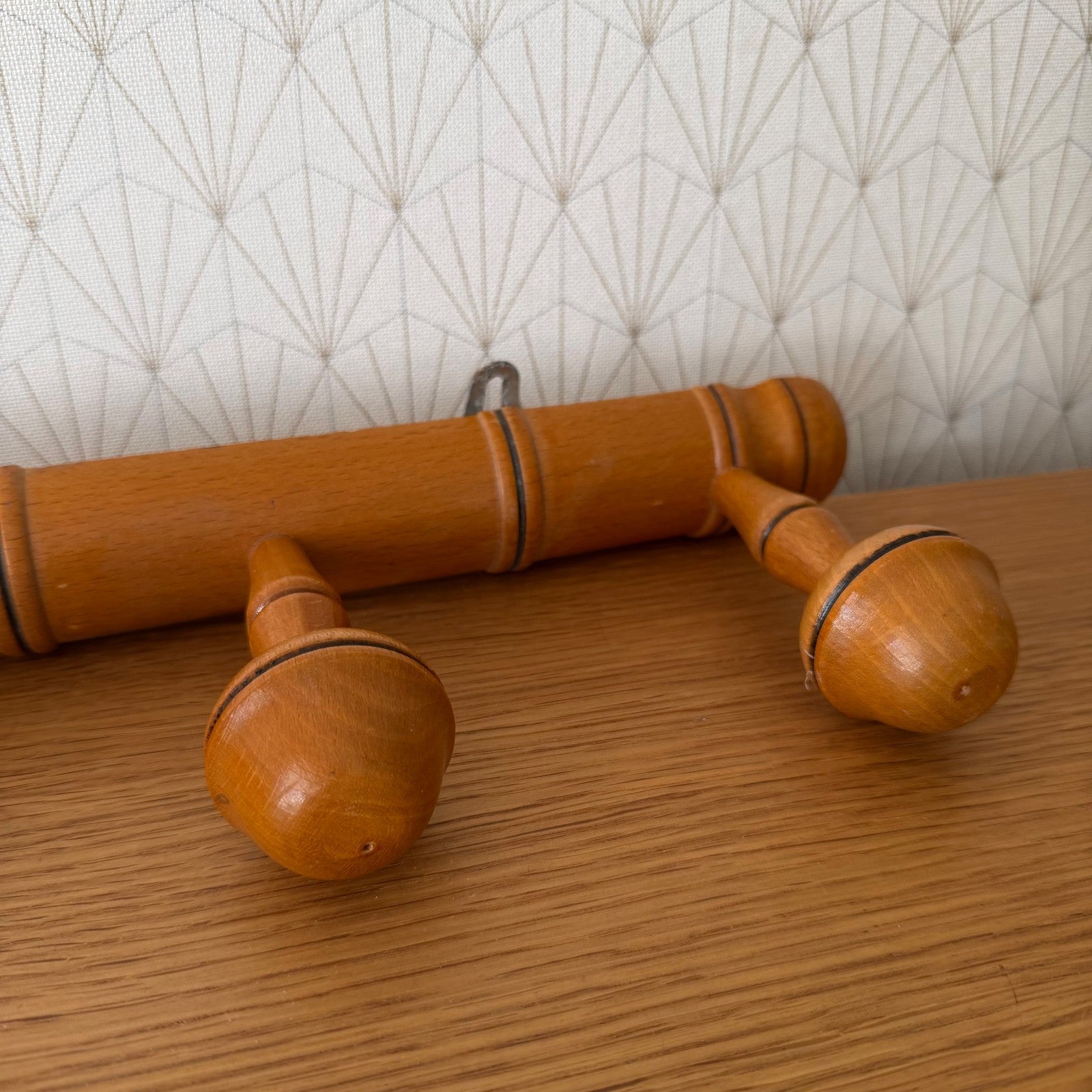 Angled view of bamboo wall-mounted coat rack with five functional hanging pegs