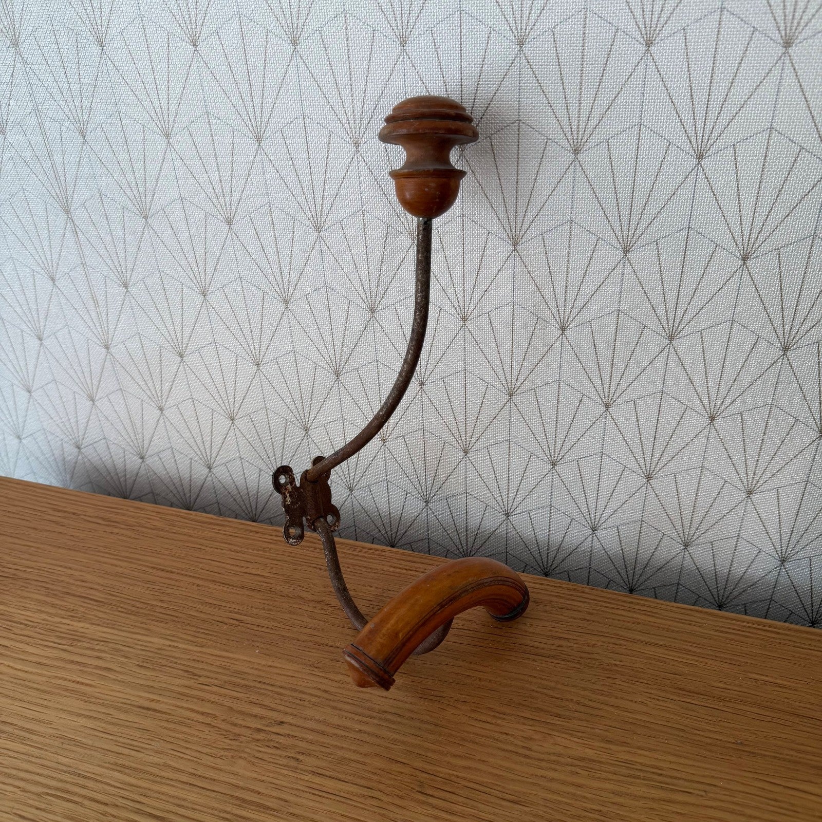 Full view of antique French coat hook with original mounting hardware and elegant swing arm design