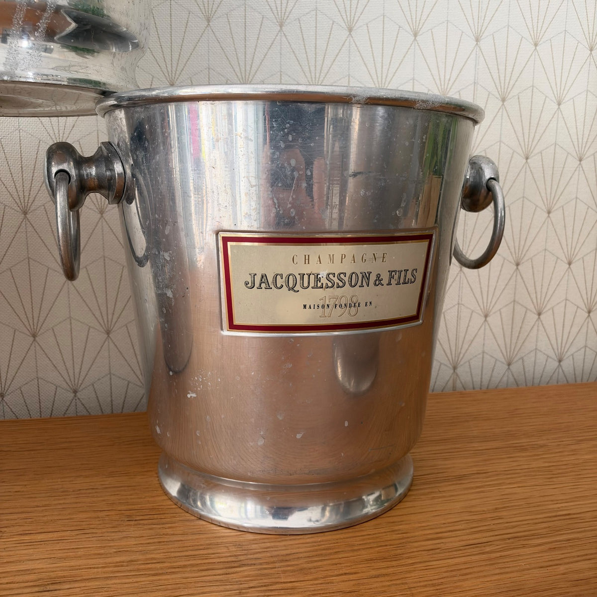 Vintage French champagne bucket with red and cream label and cast metal handles, side view