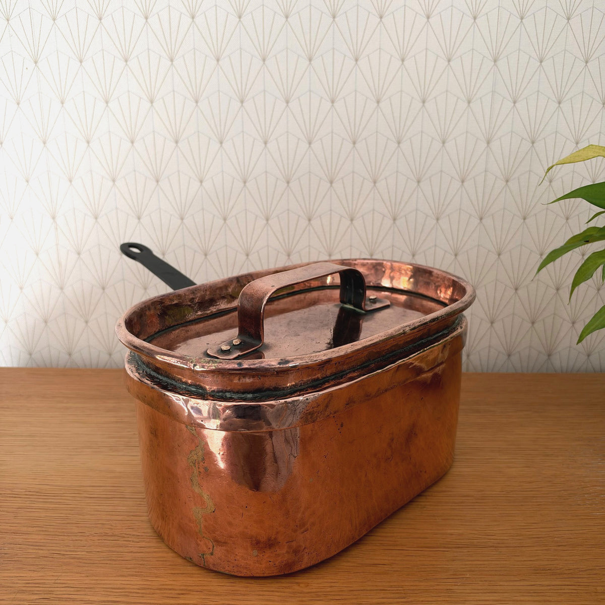 Antique French copper braising pan with fitted lid and black wrought-iron handle, oval form