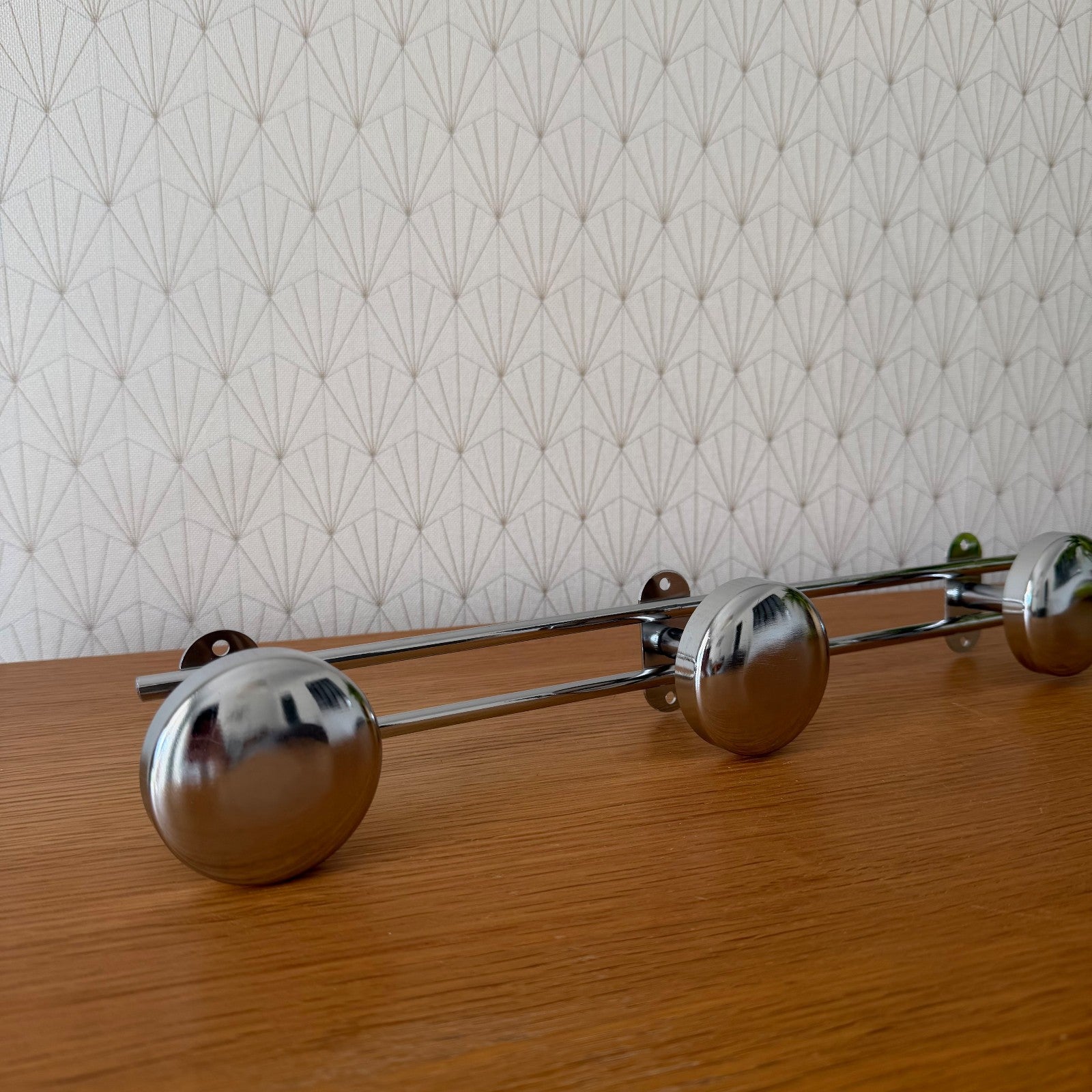 Close-up of chrome coat hooks showing mirror-like polished finish and mounting hardware detail
