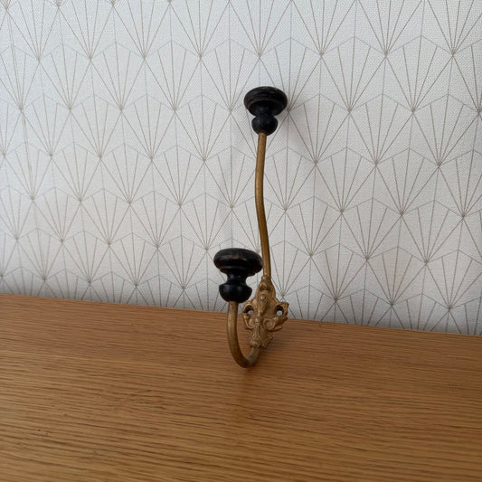 Vintage French metal wall hook with brass ornamental bracket and black wooden knob, full view