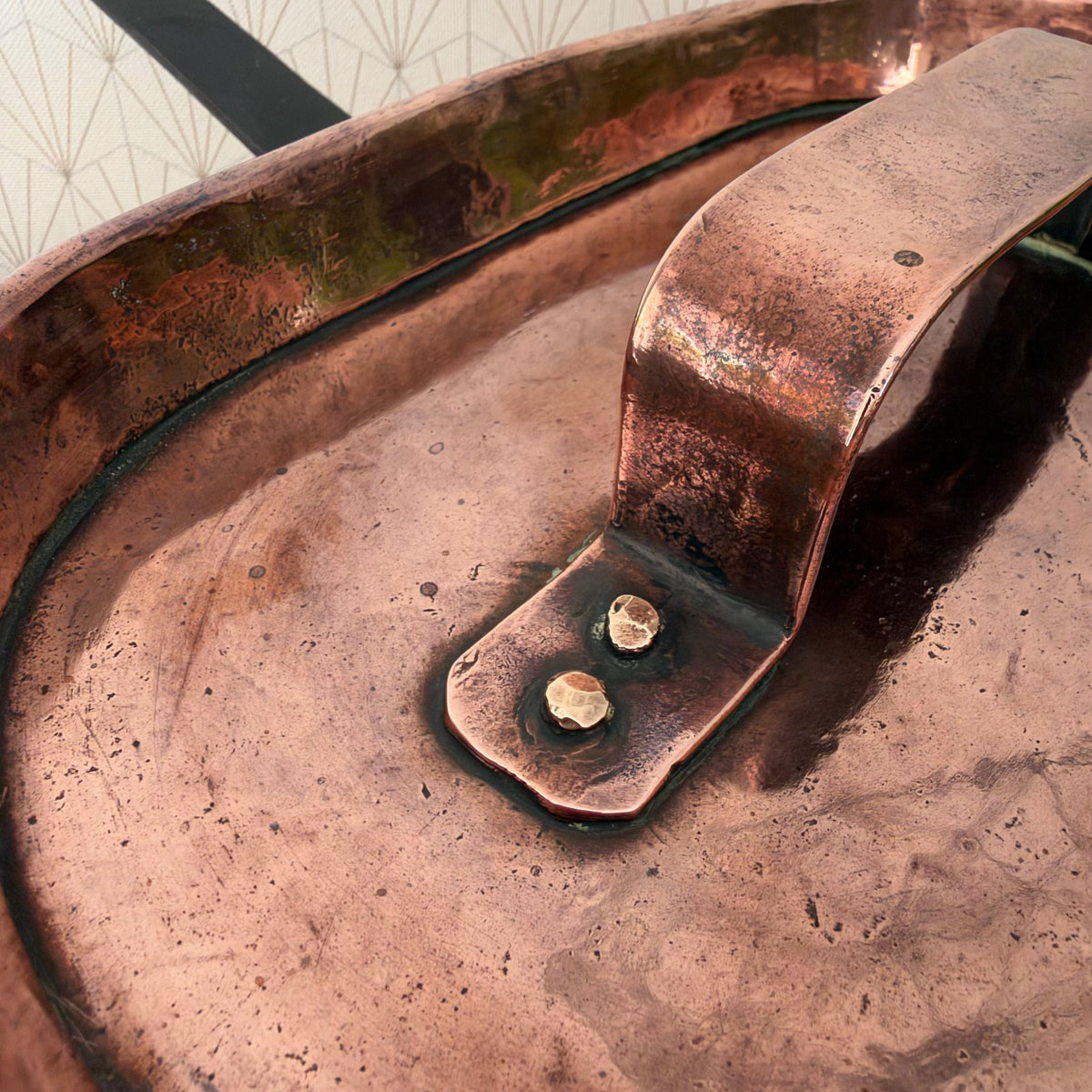 Detail of copper handle attachment and rivets on vintage French braising pan lid