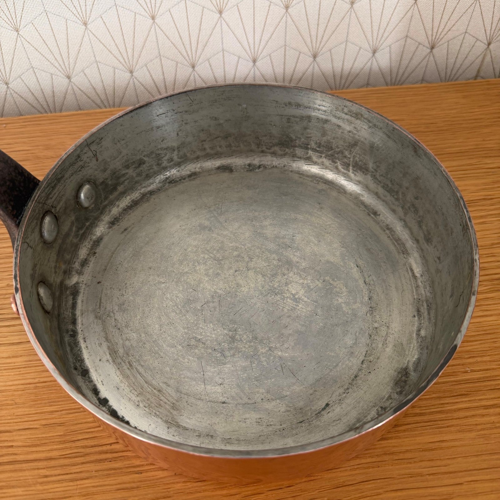 Interior view of tin-lined copper saute pan showing patina and wear from use